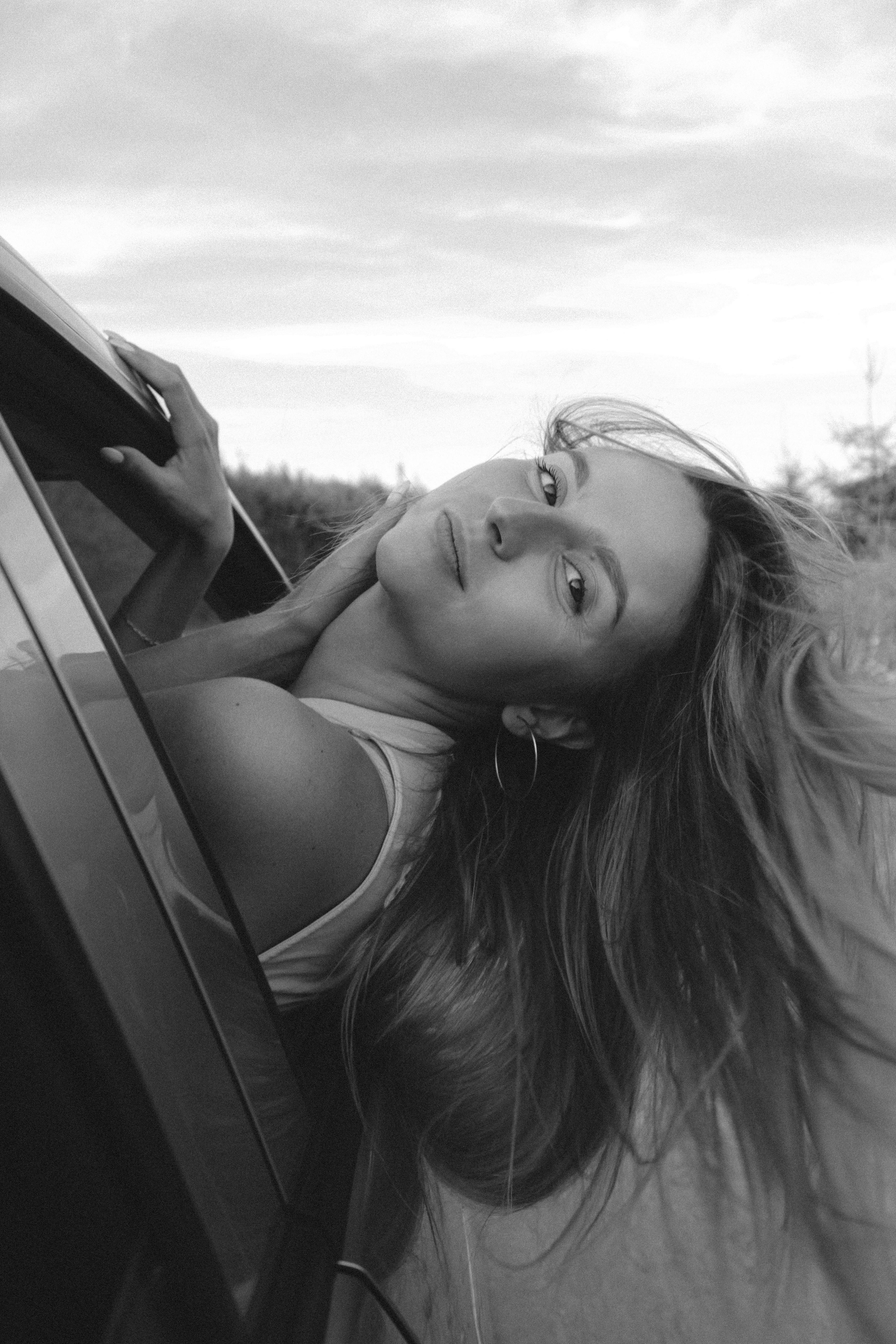 grayscale photo of woman looking out of a vehicle window