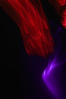 Dynamic abstract light streaks in vibrant red and purple on black.