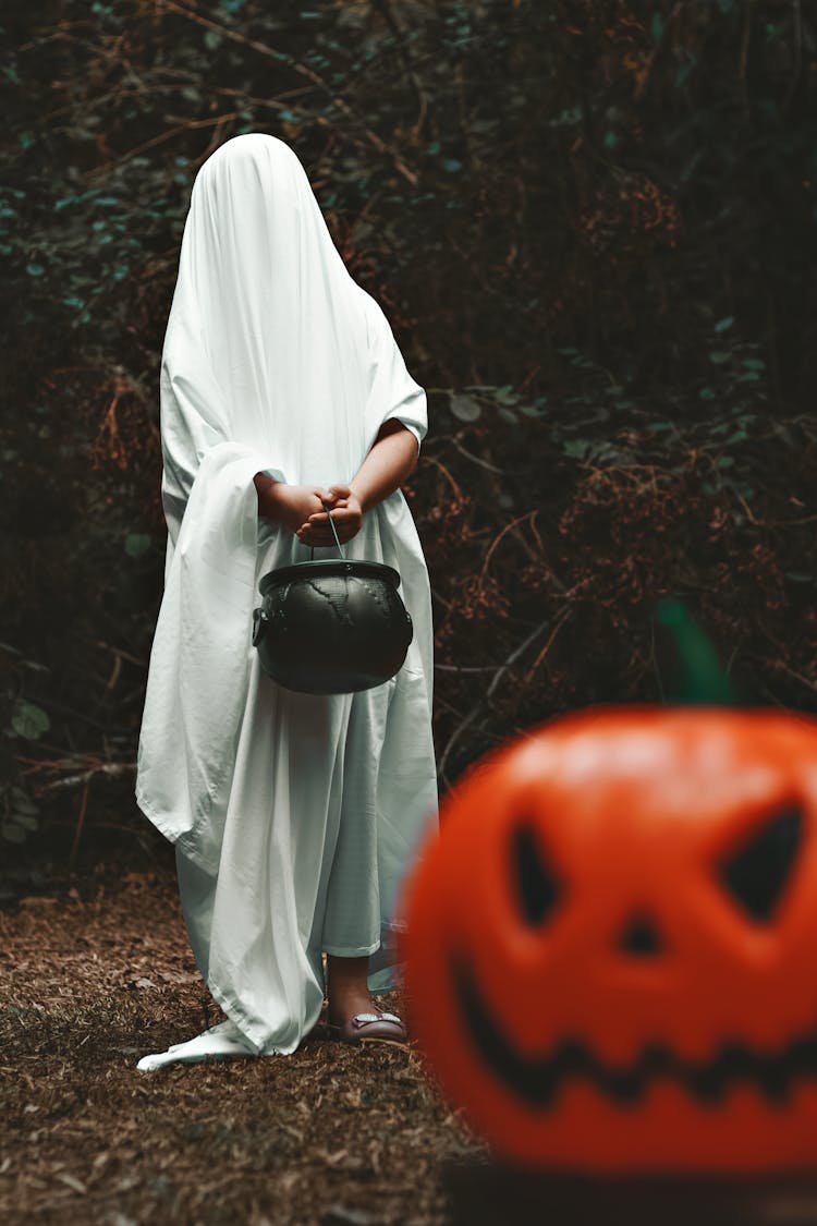 Person In White Ghost Cover In Dark Forest