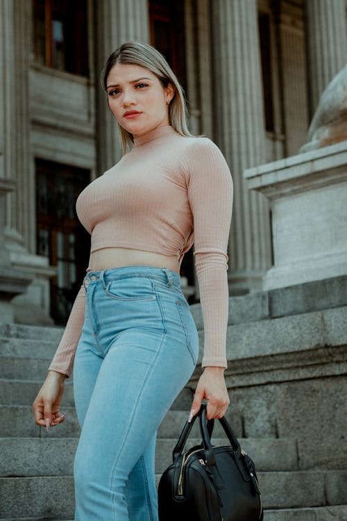 Woman in Crop Top and Denim Jeans Sitting while Seriously Looking at the  Camera · Free Stock Photo