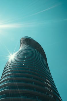 镜头捕捉了一座引人注目的扭曲摩天大楼，伴有太阳耀斑和玻璃反射