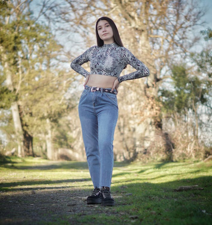 Woman in Crop Top and Denim Pants Standing on a Pathway · Free Stock Photo