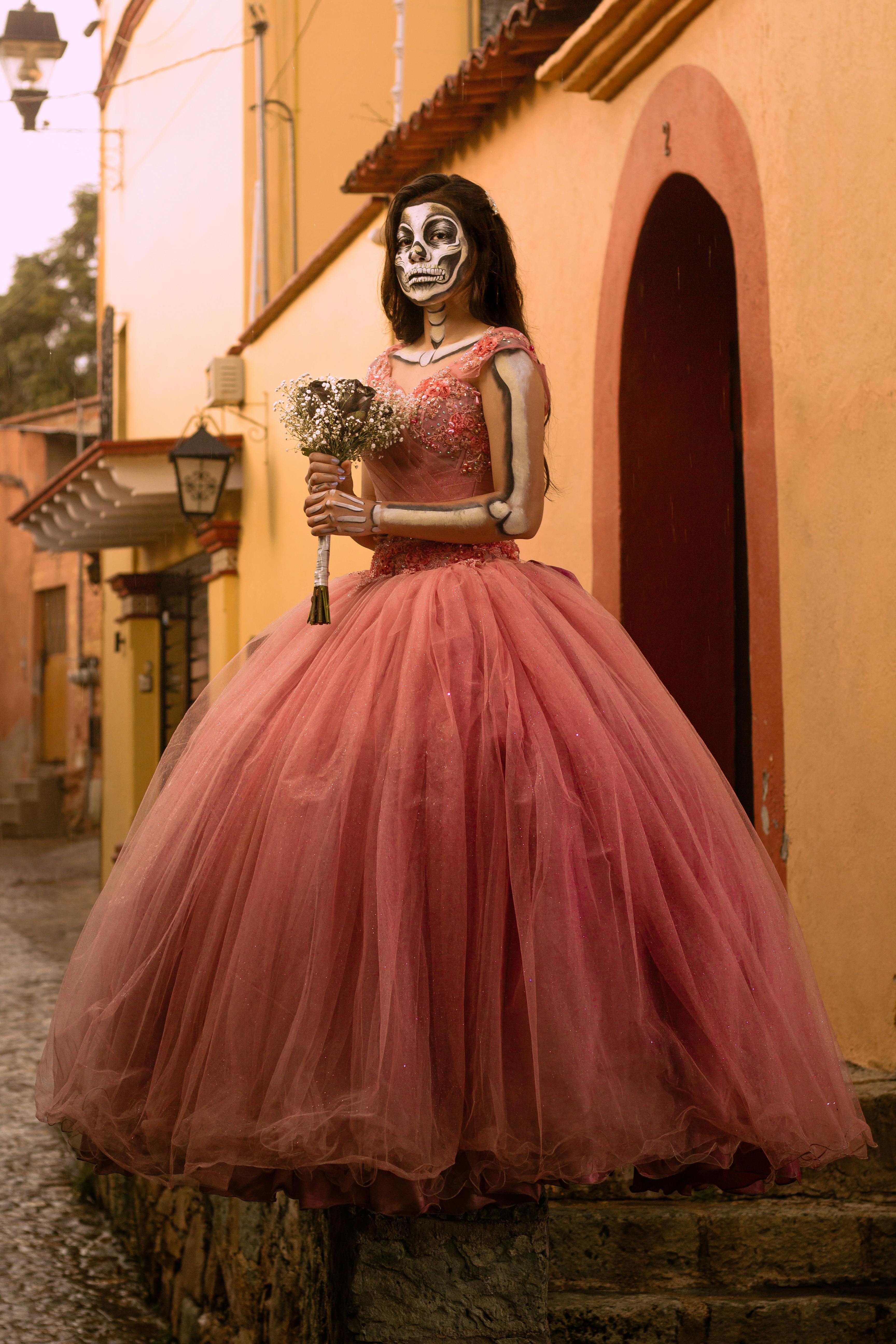 Woman in skeleton makeup and pink gown celebrates Day of the Dead in Oaxaca, Mexico.