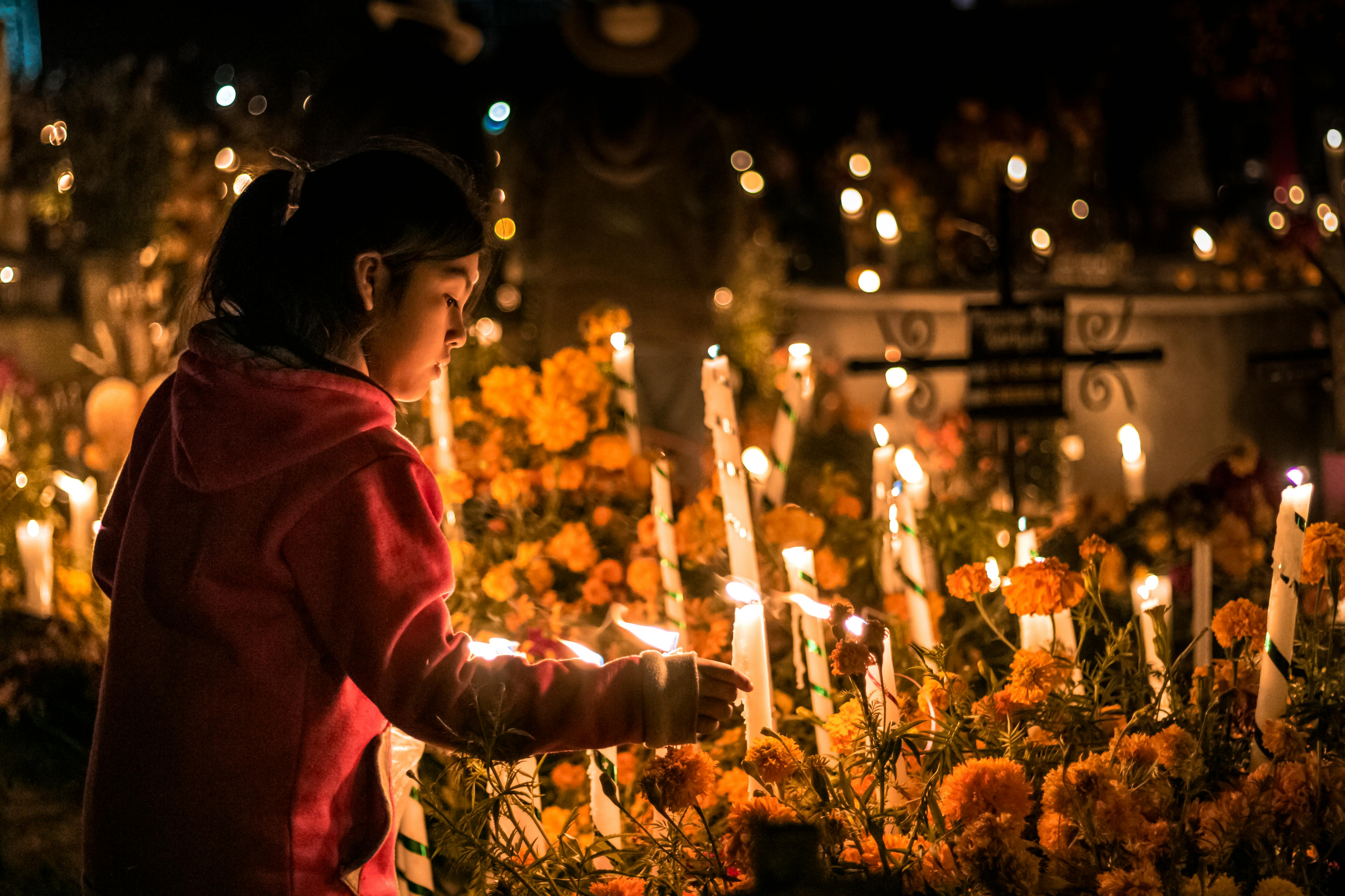 A young girl lighting candles at a Día de los Muertos cemetery in Oaxaca.