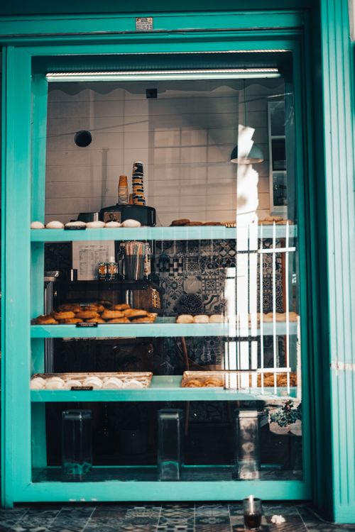 Free An inviting bakery window with a teal frame showcasing a variety of baked goods and pastries. Stock Photo