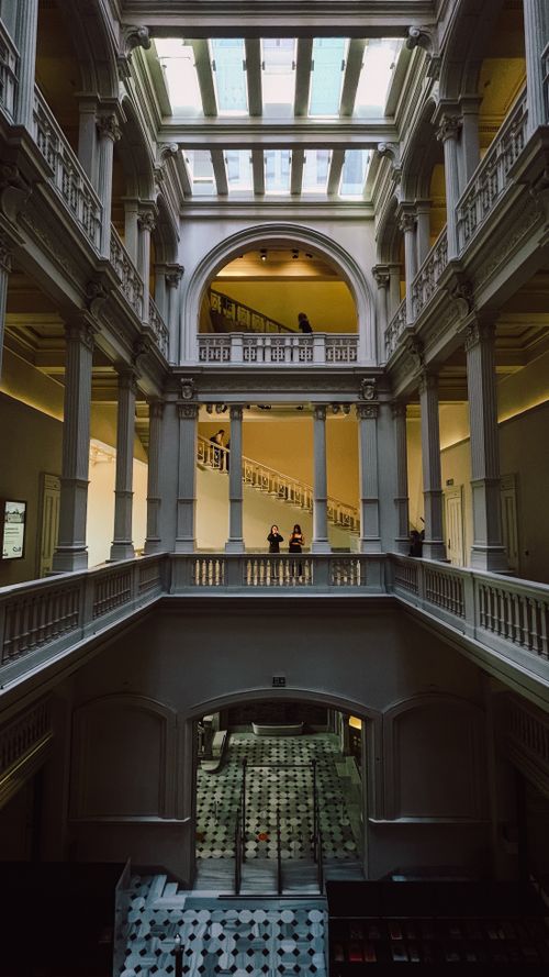 Free Captivating view of a historical building's grand interior with columns and skylight, featuring few people. Stock Photo