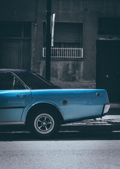 Side view of a classic blue car parked on a street in Barcelona, Spain. Urban setting.