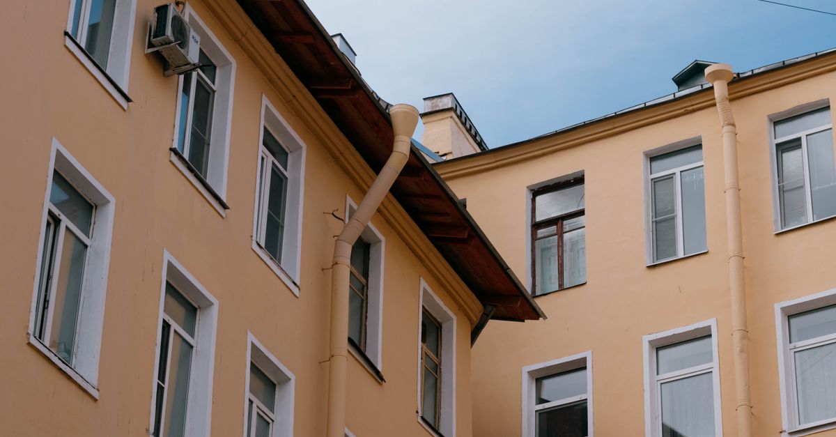 Low angle view of yellow residential building facade with white-framed windows.