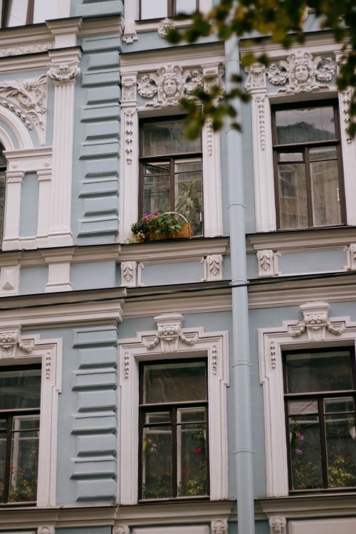 Free Elegant neoclassical townhouse facade featuring ornate designs and a subtle blue color scheme. Stock Photo