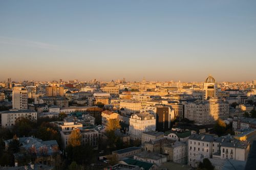 Free A stunning aerial view of a cityscape with buildings basking in the warm glow of the sunset. Stock Photo