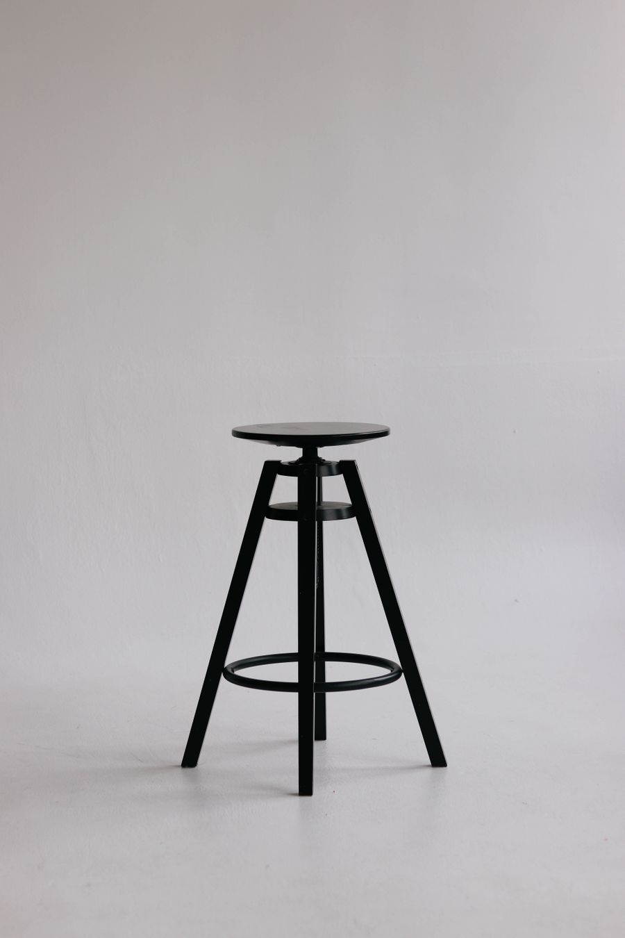 Black tripod stool photographed against a pale wall — photo by Valeria Nikitina on Pexels