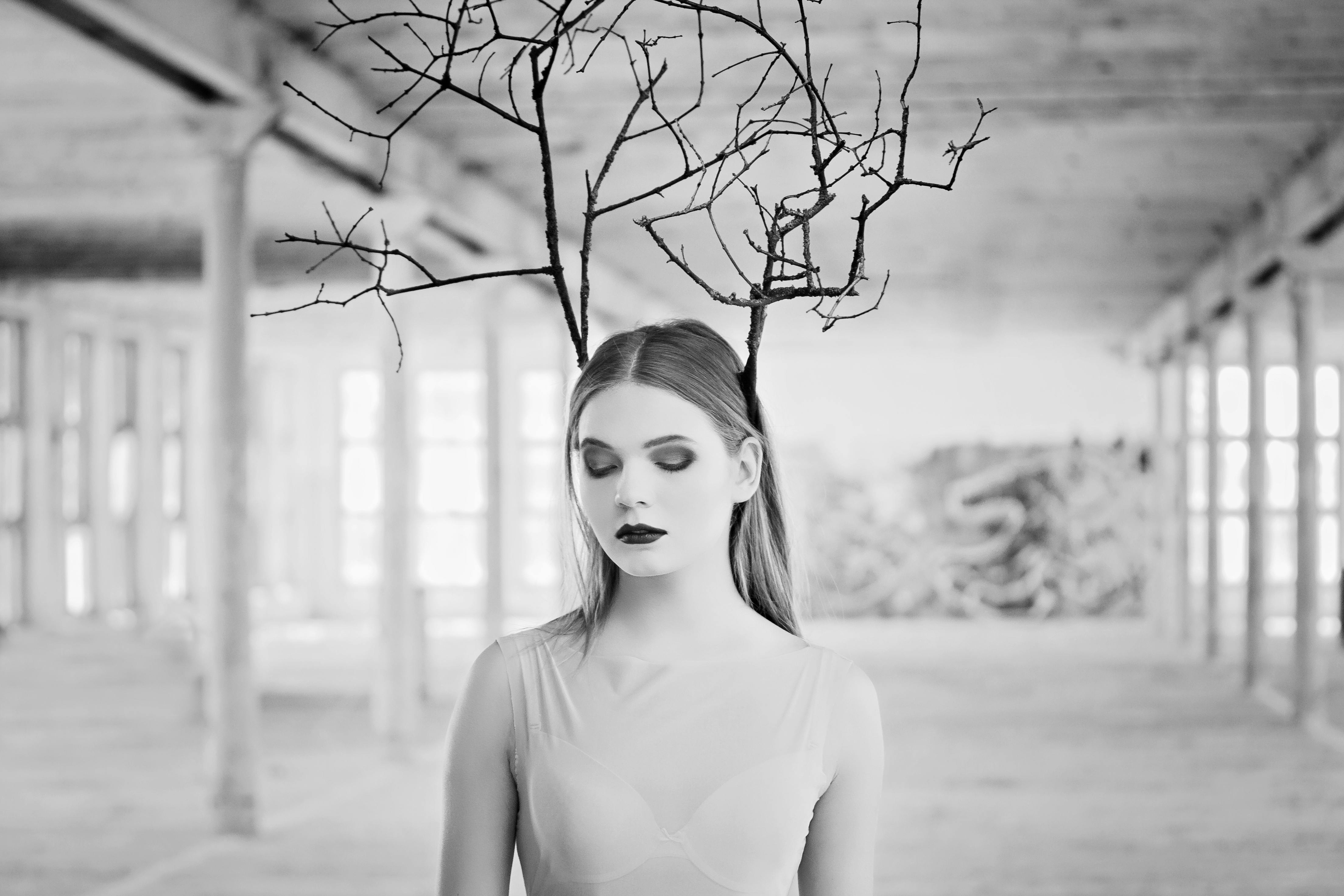 一幅描绘了树枝女人的创意黑白肖像，置于质朴的室内环境中