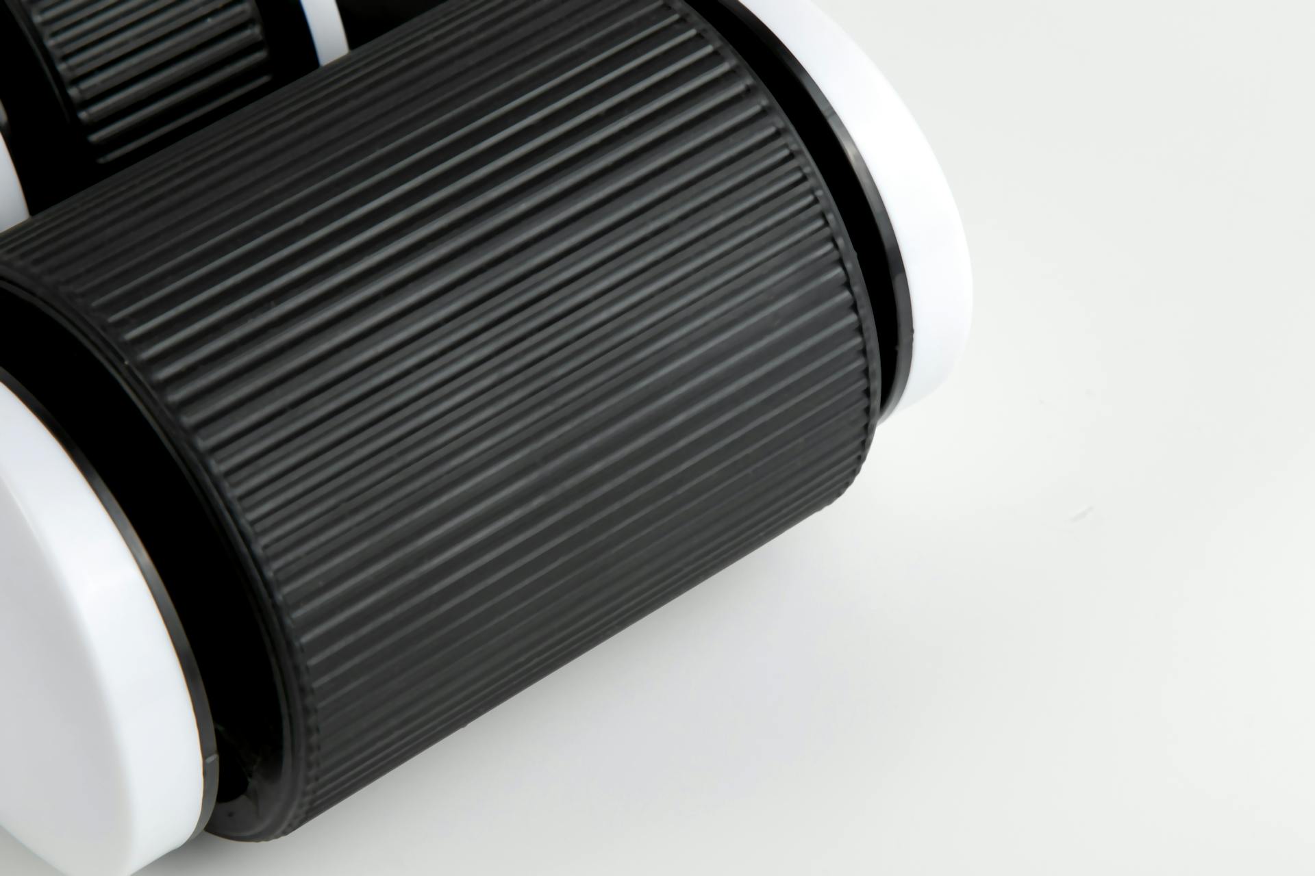 High-resolution close-up of a textured, black and white cylindrical object on a light background.