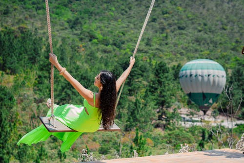 Free Woman in a Green Dress Using a Swing Stock Photo