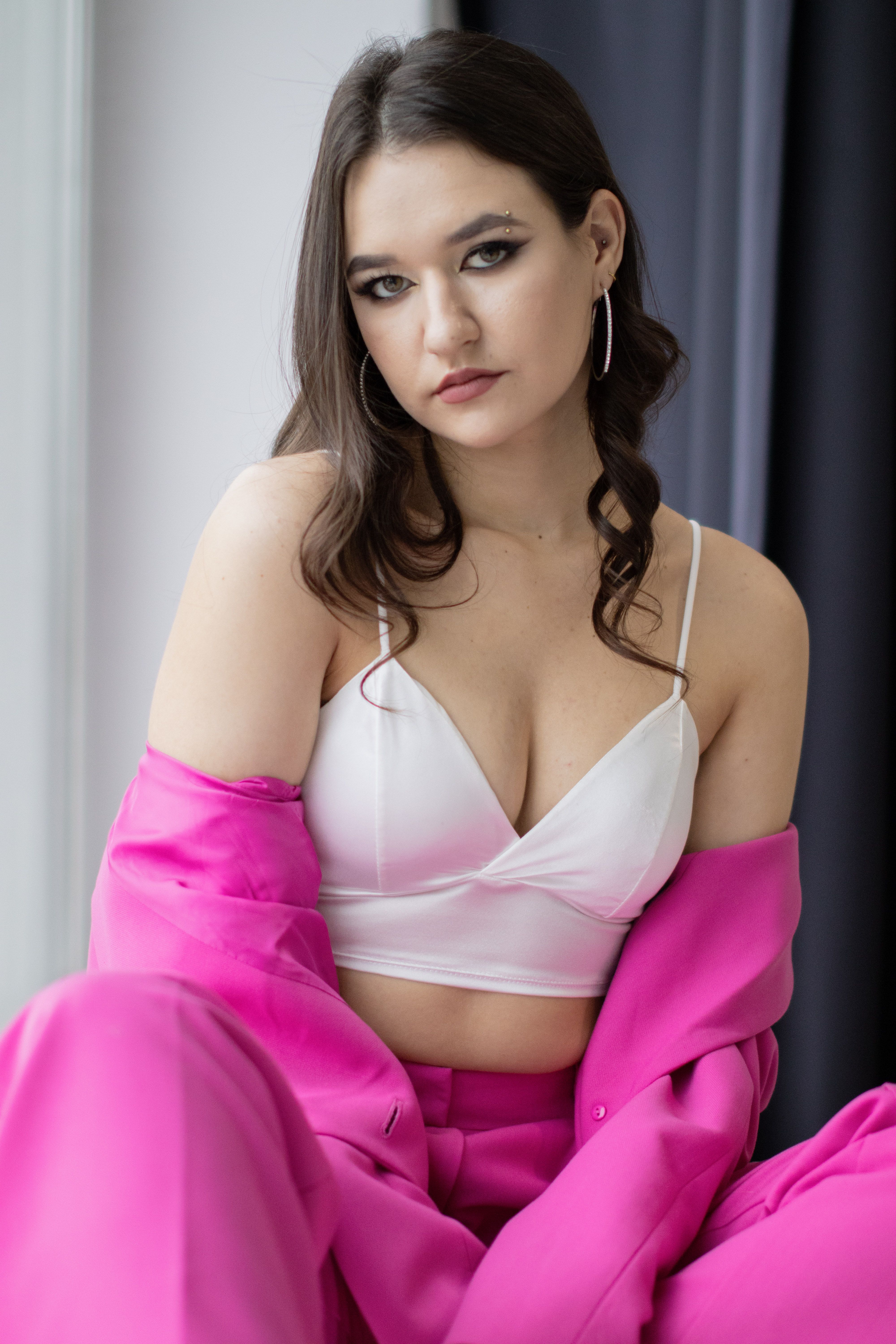 Fashionable woman in pink suit posing indoors, exuding confidence and elegance.