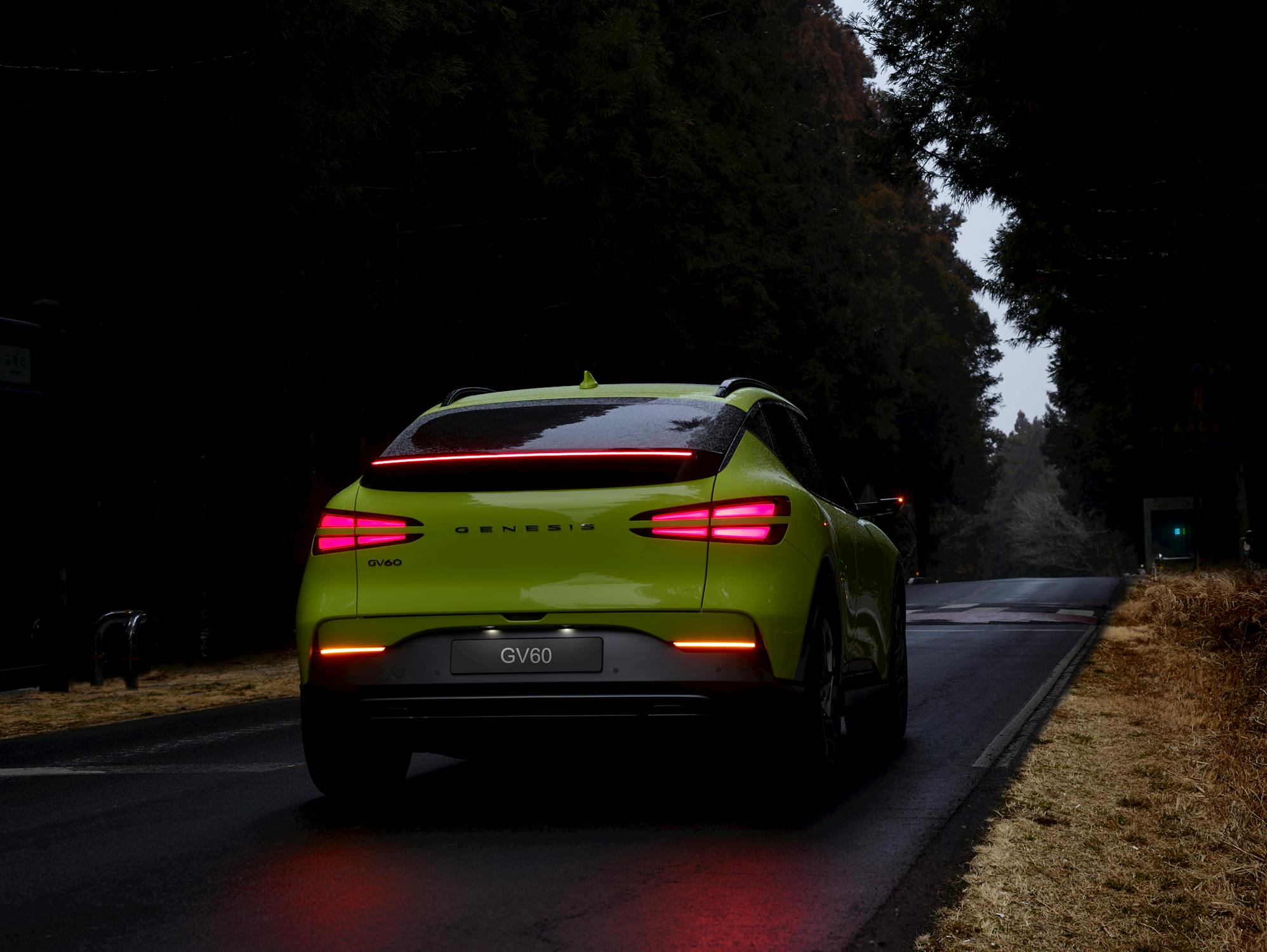 Lime Green Genesis GV60 SUV on Forest Road