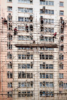 High-rise building in Hong Kong with bamboo scaffolding and construction workers in Kowloon.
