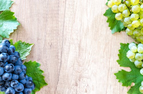 Blue Berries and Green Grapes on Beige Wooden Surface
