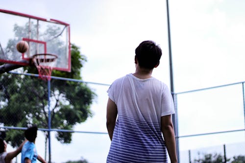 赤いバスケットボールのフープシステムの近くに立っている男