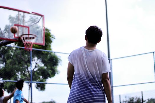 Young men play basketball outdoors, capturing the joy and energy of the game.