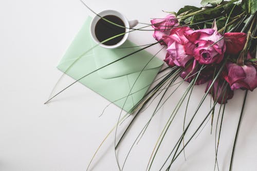 Ramo De Flores Rosas Junto A Taza De Cerámica Blanca