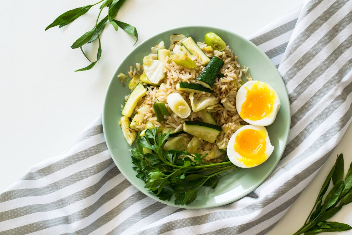 Free Fried Rice With Poached Egg, Zucchini, And Celery on Round Green Ceramic Plate Stock Photo