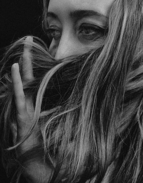 Grayscale Photo of a Woman Touching Her Hair