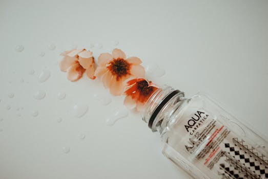 Creative composition showing flowers and water droplets with an Aqua Carpatica bottle on white background.
