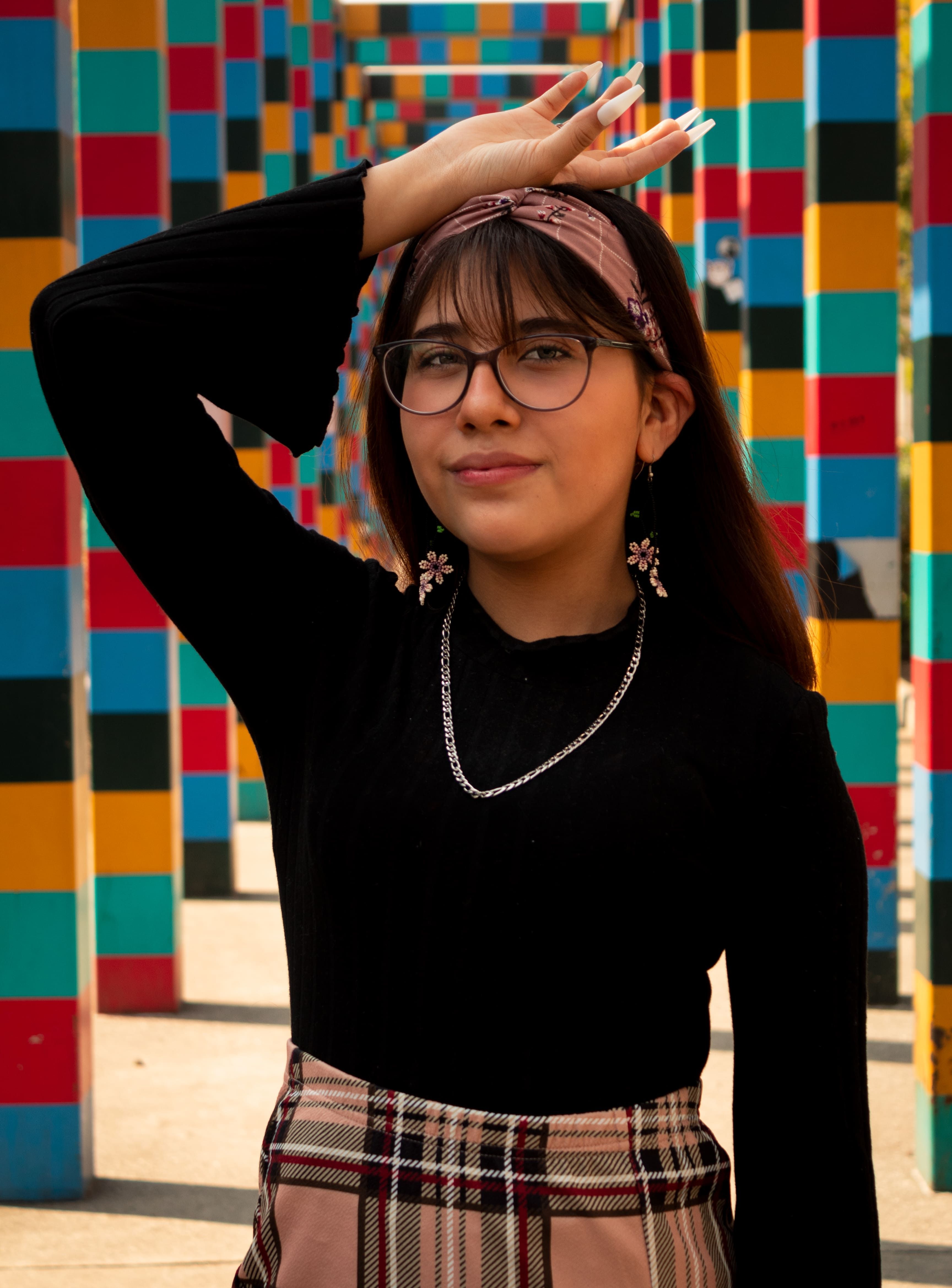 Young woman in glasses poses confidently in a vibrant plaza in Mexico City.