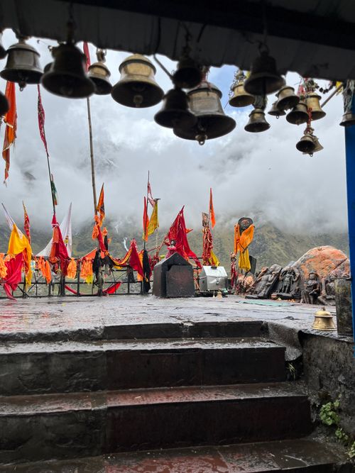 Free A tranquil mountain shrine adorned with vibrant flags and bells amidst misty clouds. Stock Photo