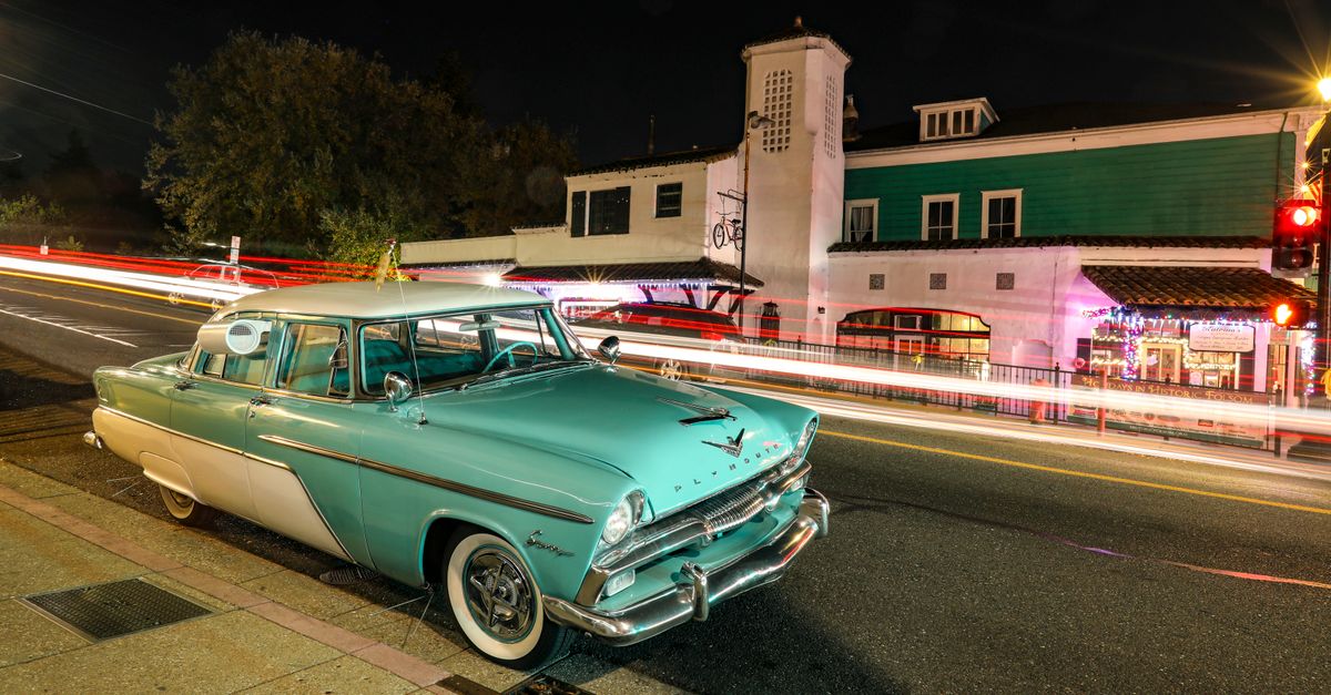A vintage Plymouth car parked on an illuminated street in Folsom, CA, capturing vibrant urban night life.