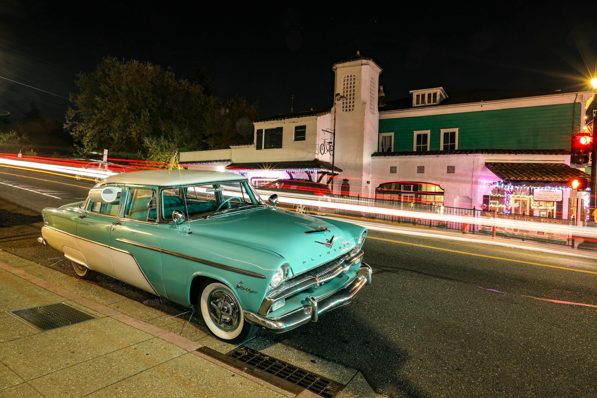A vintage Plymouth car parked on an illuminated street in Folsom, CA, capturing vibrant urban night life.