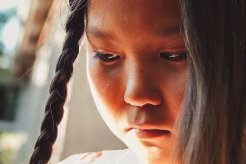Free Close-up portrait of a young girl with braids, expressing a thoughtful and introspective mood. Stock Photo