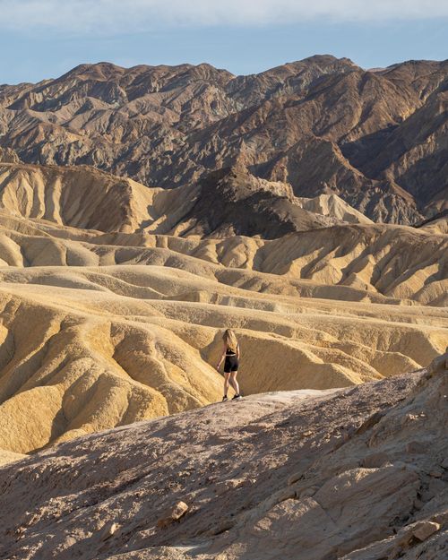 Free A lone hiker explores the rugged terrain of Death Valley National Park under the bright desert sun. Stock Photo