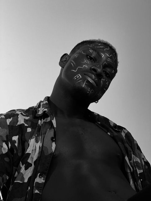 Artistic monochrome portrait of a man with face paint depicting abstract symbols.