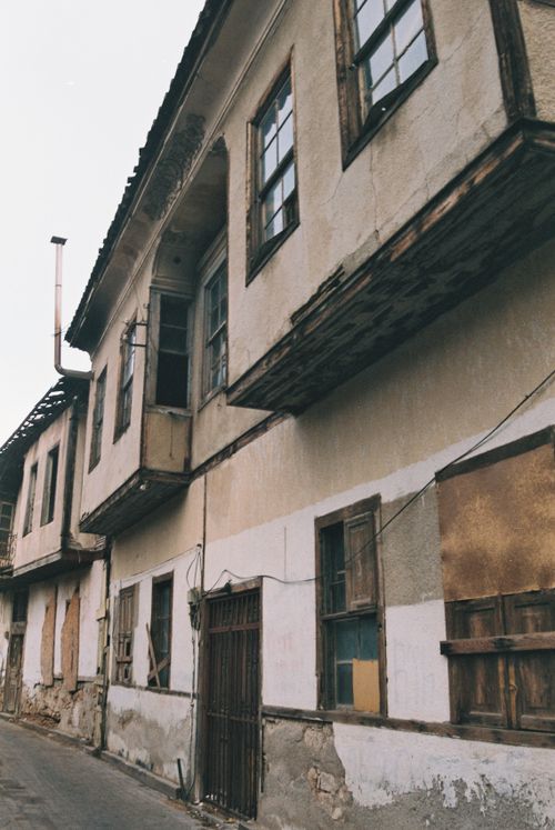 Free A narrow street view of an abandoned building with a weathered facade and broken windows. Stock Photo