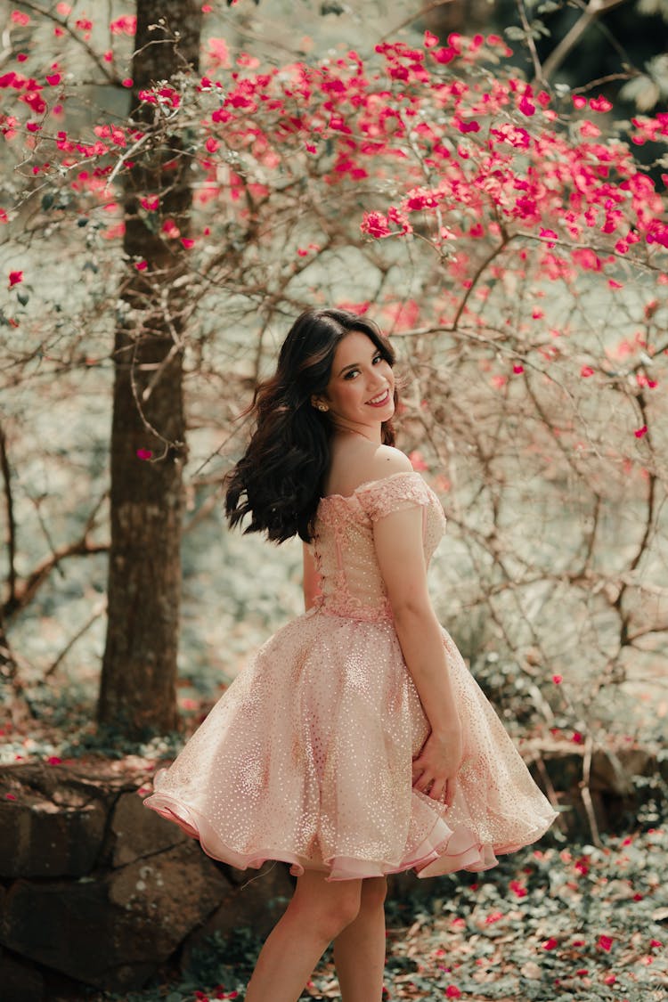 A Woman In Pink Dress Smiling While Looking Over Shoulder