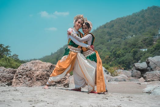 Two dancers in traditional Odissi attire perform on Puri Beach, India, showcasing classical dance elegance.