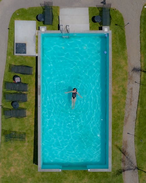Drone Shot of a Woman Swimming in a Swimming Pool