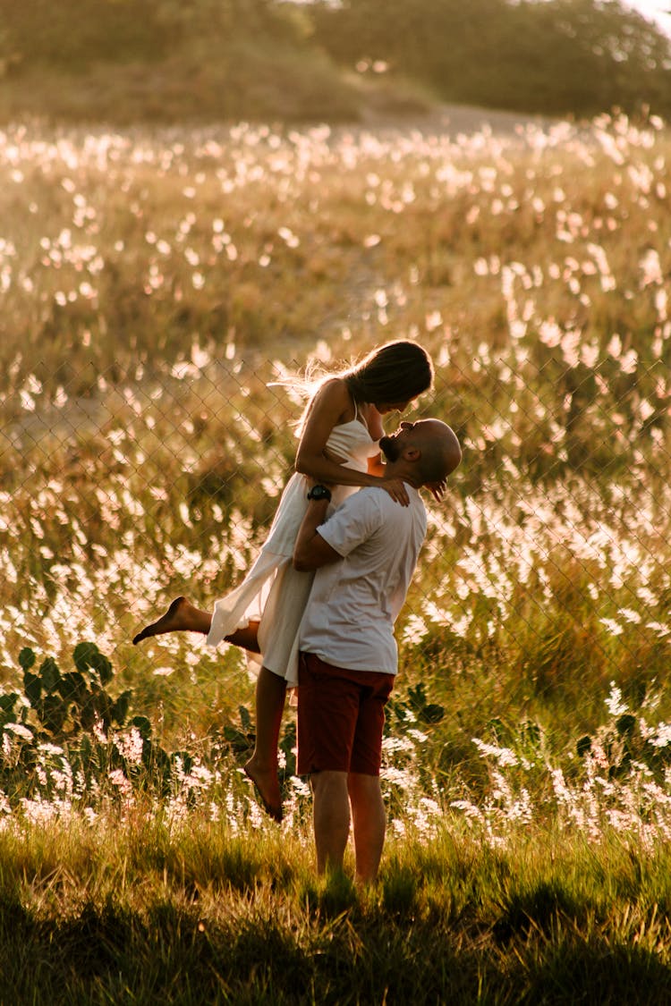 Photo Of A Man Carrying A Woman In A Grass Field