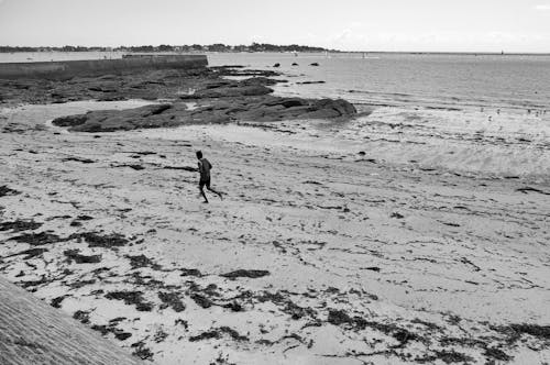 Grayscale Photograph of a Person Running on the Sand