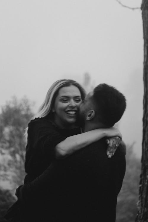 Grayscale Photo of a Man Kissing a Woman