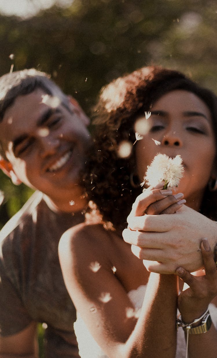 A Woman Blowing A Dandelion Flower