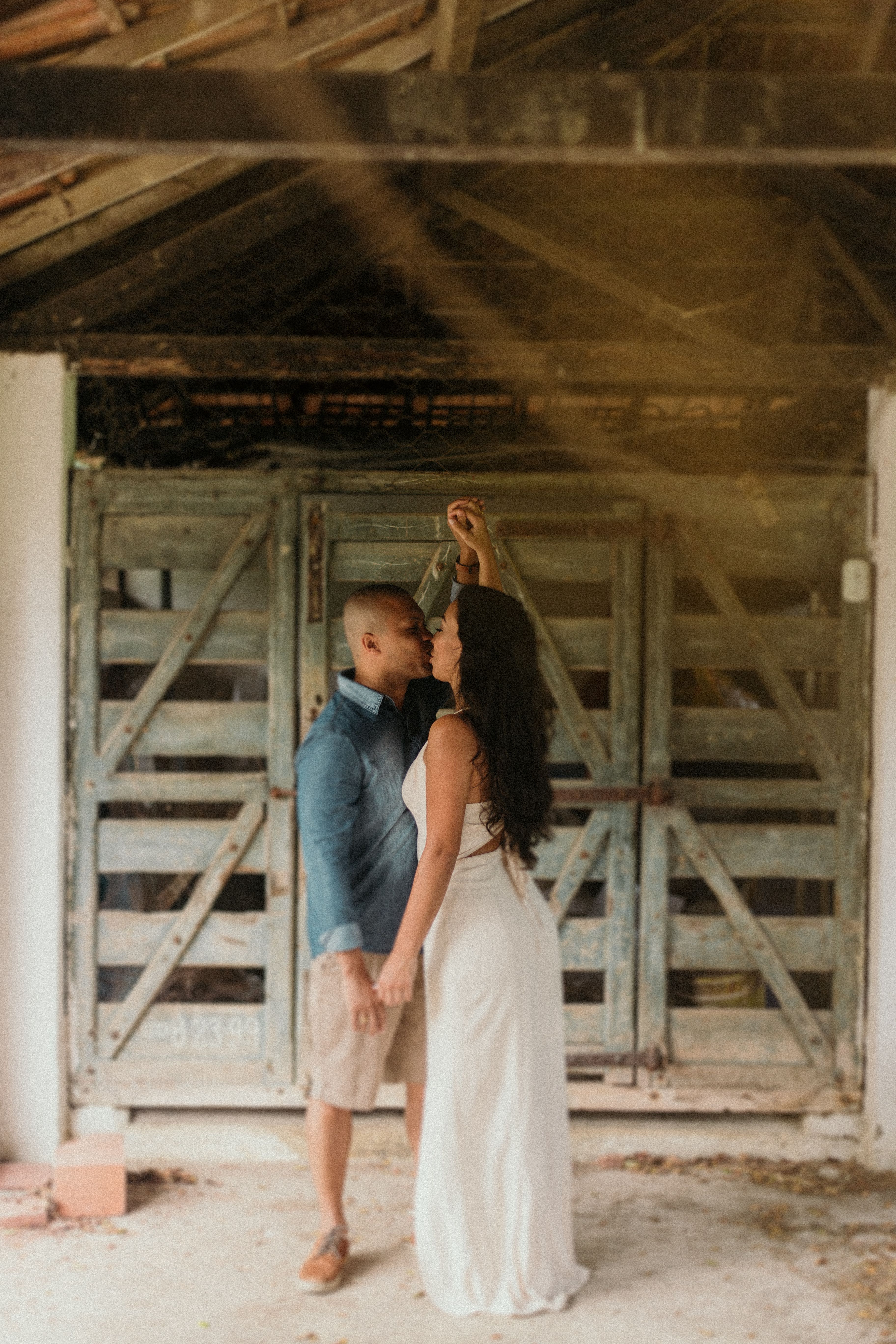 A couple shares a tender moment in front of a vintage barn door, exuding love and intimacy.