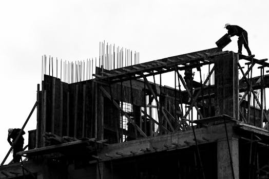 Black and white silhouette of workers on a building site. Dramatic and industrial.