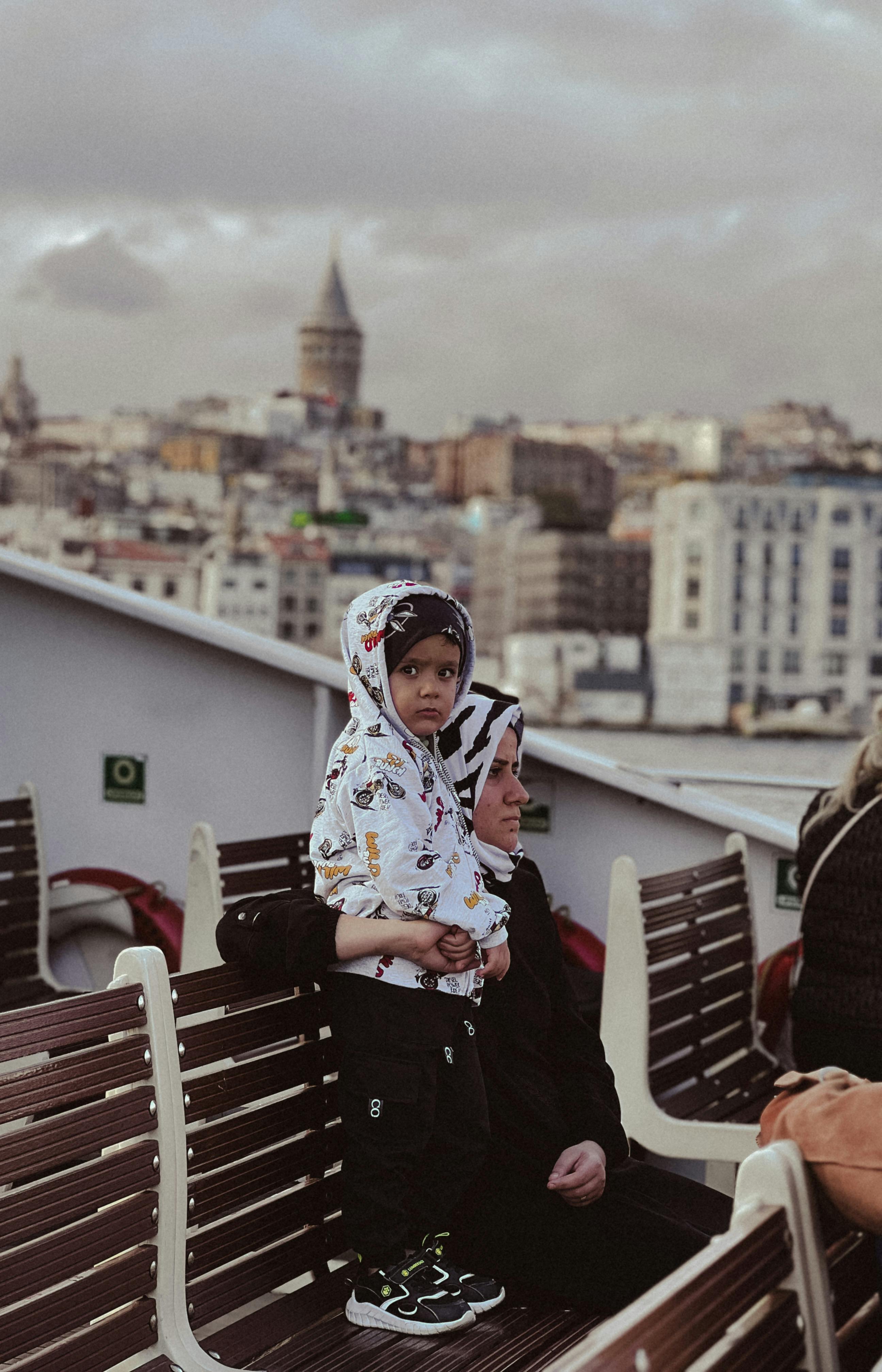 a girl with hijab standing on bench beside woman in black and white hijab