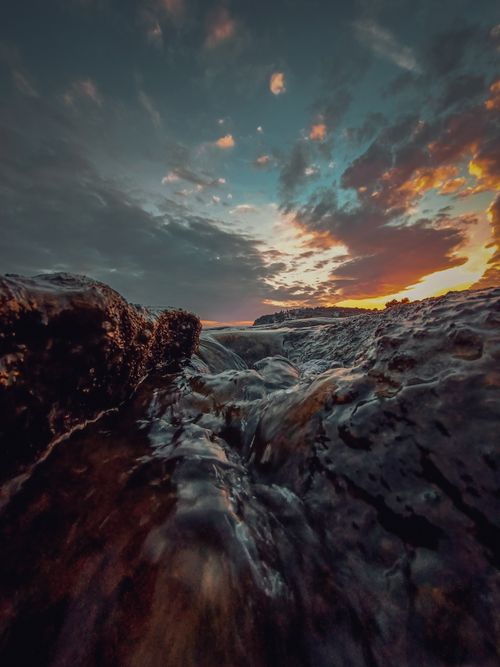 Free A vibrant sunset reflecting over rocks and flowing water in Yumurtalık, Adana, Turkey. Stock Photo