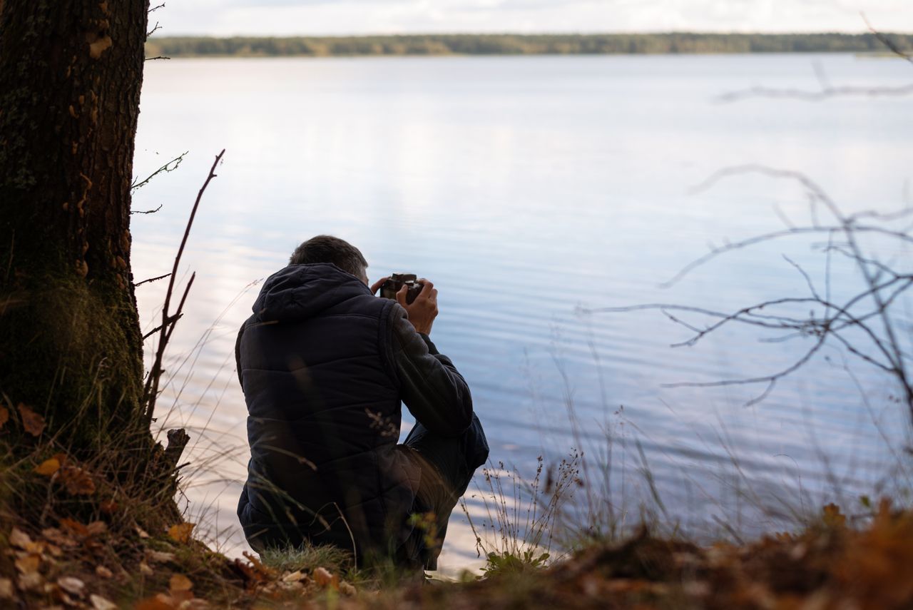 man photographing serene lakeside atmosphere surrounded by nature