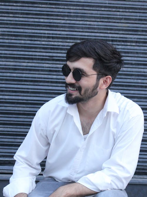 A Handsome Man in White Long Sleeves Smiling while Wearing Sunglasses