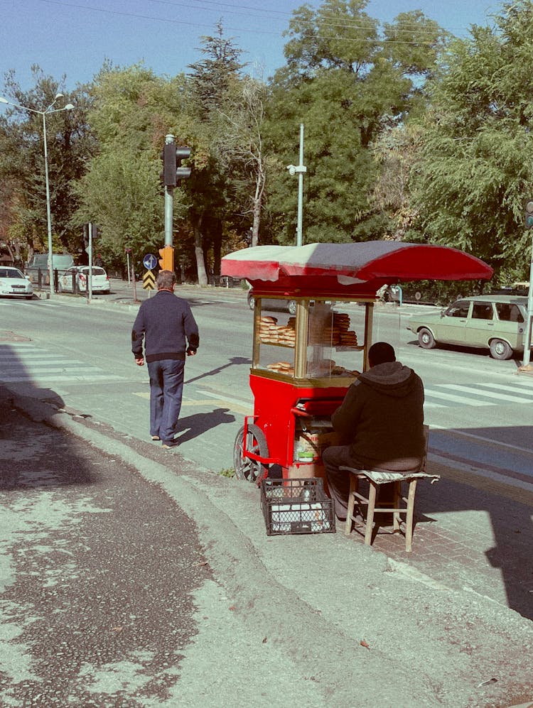 Person Walking On A Pedestrian Lane Near A Street Vendor